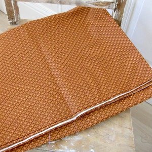 Peut inclure: Un morceau de tissu plié avec un motif brun et blanc. Le tissu a un petit motif répétitif de fleurs brunes sur un fond blanc.