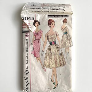 Könnte beinhalten: Vintage Simplicity Schnittmusterpackung mit Illustrationen von Damenkleidern. Die Packung ist cremefarben mit Text und Illustrationen in Schwarz, Rosa und Grün. Die Packung enthält die Nummer 3045 und Maße in Zentimetern.