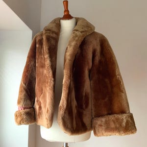 Puede incluir: Chaqueta de piel sint&eacute;tica marr&oacute;n con cuello ancho y pu&ntilde;os. La chaqueta se exhibe en un maniqu&iacute;. Los pu&ntilde;os revelan un toque de forro rosa. La chaqueta es de longitud media.