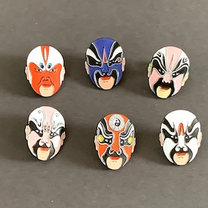 Könnte beinhalten: Sechs farbenfrohe chinesische Opernmasken mit aufwendigen Designs. Die Masken sind aus Kunststoff und haben eine glänzende Oberfläche. Die Masken sind alle in verschiedenen Farben gehalten und haben unterschiedliche Gesichtsausdrücke.