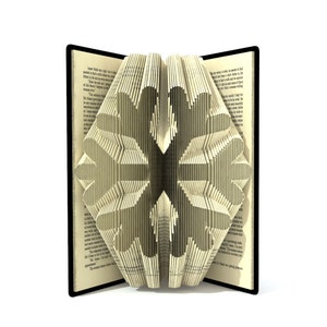 May include: A book with pages folded into a three-dimensional snowflake design. The book is open and the snowflake is visible in the center of the image.