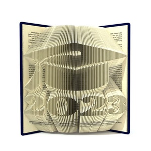 Könnte beinhalten: Ein Buch mit Seiten, die zu einem 3D-Design eines Fisches und einer Schüssel gefaltet sind. Das Buch ist geöffnet und die Seiten sind gefaltet, um einen dreidimensionalen Effekt zu erzeugen. Das Buch ist blau und die Seiten sind cremefarben.
