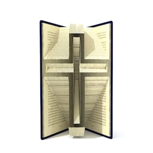 May include: A book with pages folded to create a three-dimensional cross. The book is open and the cross is visible in the centre of the image. The book has a blue cover.