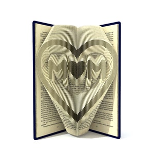 Könnte beinhalten: Ein Buch, dessen Seiten zu einem Herz gefaltet sind, mit dem Wort "MOM" darin. Das Buch ist geöffnet und das Herz steht auf.