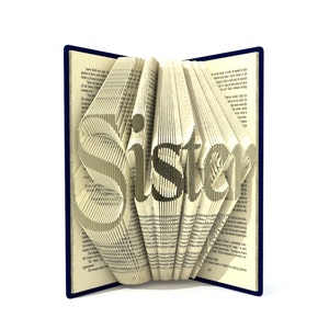 May include: A book with the word "Sister" folded into the pages. The book is open and the pages are folded to create a 3D effect. The book is on a white background.