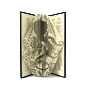 May include: A book with pages folded into a 3D design of an octopus. The book is open and the octopus is facing the viewer. The book is on a white background.