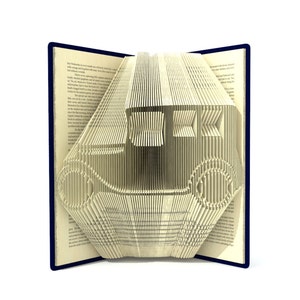 Peut inclure: Un livre dont les pages sont pliées en forme de voiture ancienne. La voiture est en papier et de couleur beige clair. Le livre est ouvert et la voiture est visible au centre du livre.