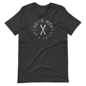 May include: Dark heather grey t-shirt with a white graphic of crossed skis and the text "GORE MTN NEW YORK" in a circle.