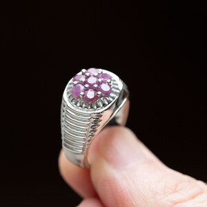 Peut inclure: Une bague en argent avec un groupe de pierres précieuses roses serties au centre. La bague a une bande texturée.