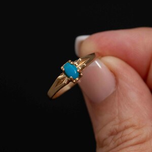 May include: A gold ring with a turquoise stone set in the center.