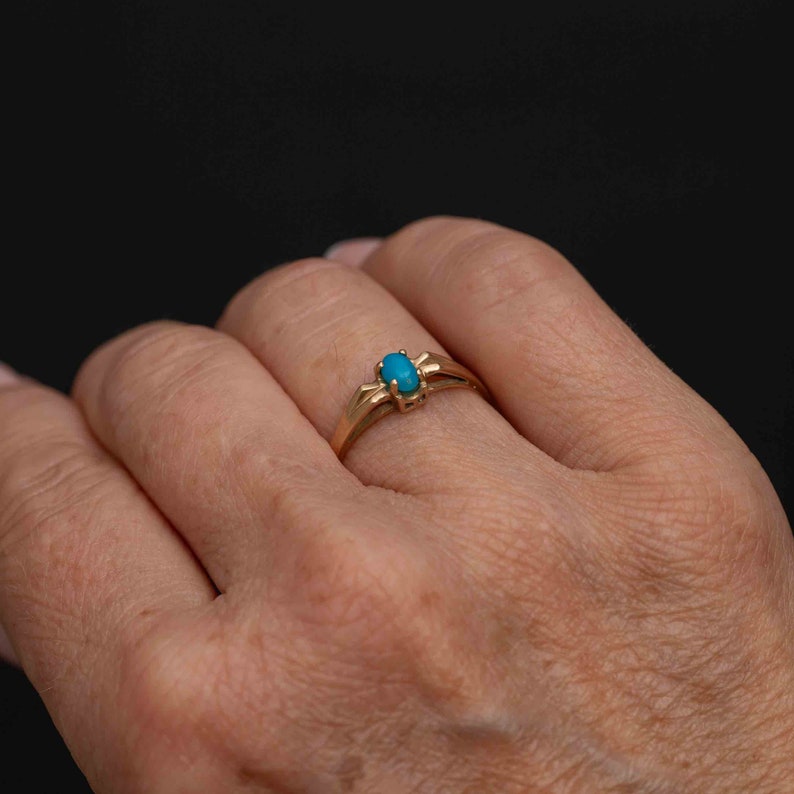 May include: A gold ring with a turquoise oval gemstone set in a simple, delicate design.
