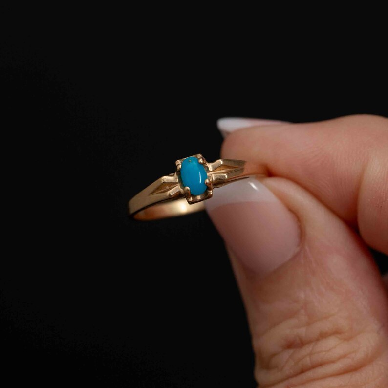 May include: A gold ring with a turquoise oval stone set in a simple design.