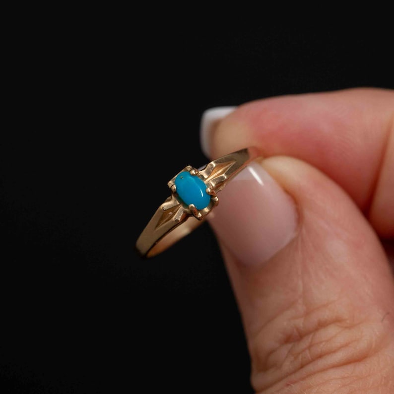 May include: A gold ring with a turquoise stone set in the center.