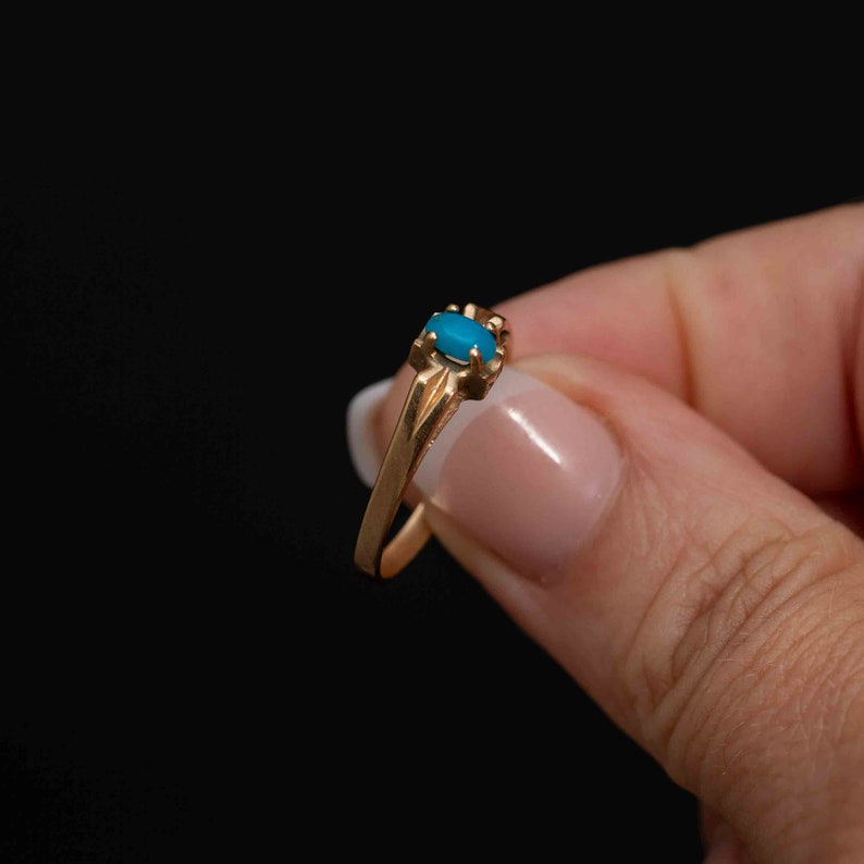 May include: A gold ring with a blue oval-shaped gemstone set in the center.