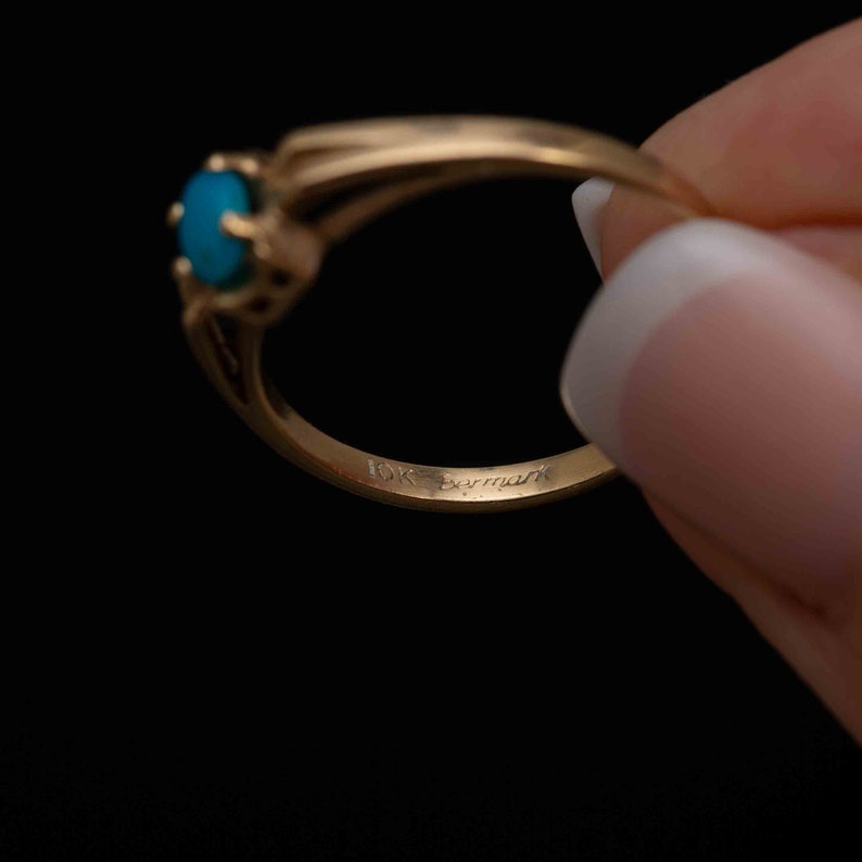 May include: A gold ring with a blue gemstone and the inscription "10K Berman" on the inside band.