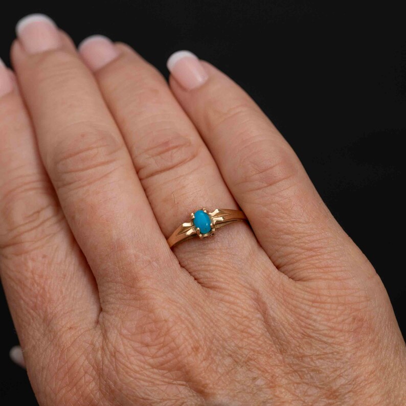May include: A gold ring with a turquoise oval gemstone set in a simple, delicate design.