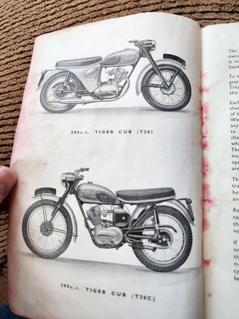 May include: Two vintage motorcycle illustrations from a book. The top image shows a motorcycle with a silver fuel tank and fenders, and the text "200c.c. TIGER CUB (T20)". The bottom image shows a similar motorcycle with the text "200c.c. TIGER CUB (T28C)".