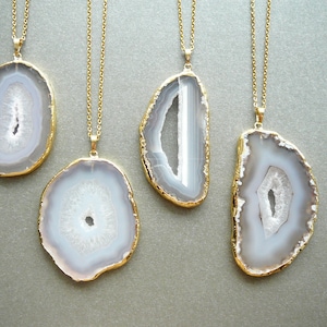 May include: Four gold necklaces with white agate pendant stones. Each pendant is a different shape and size.
