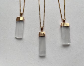 May include: Three gold necklaces with clear crystal pendants. Each pendant is a rectangular prism with a gold top.
