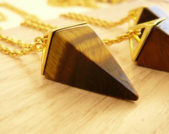 May include: A gold chain necklace with a brown and gold tiger's eye pyramid pendant.