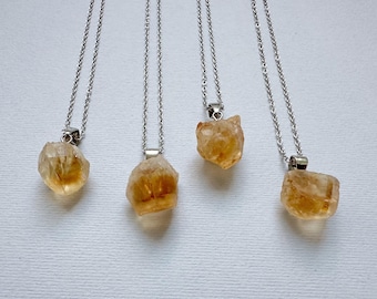 May include: Four silver chains with yellow citrine crystal pendants. The crystals are raw and have a natural, irregular shape.
