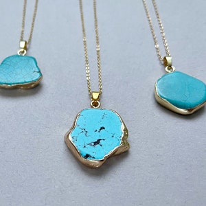 May include: Three gold chain necklaces with turquoise stone pendants. The stones are irregular in shape and have a marbled pattern.