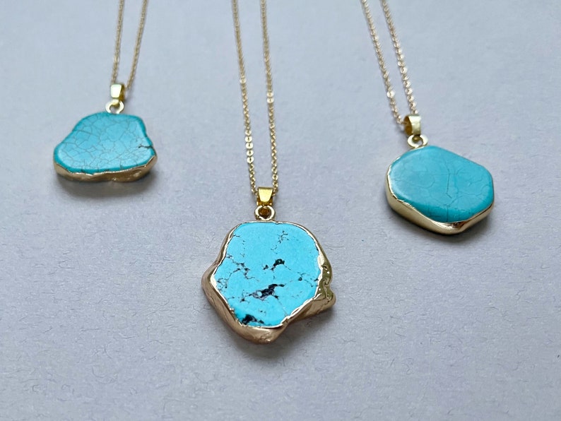 May include: Three gold chain necklaces with turquoise stone pendants. The stones are irregular in shape and have a marbled pattern.