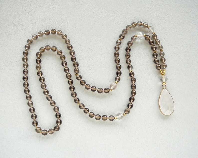 May include: A brown and clear crystal beaded necklace with a large clear crystal pendant. The necklace is made of faceted beads and has a gold accent.