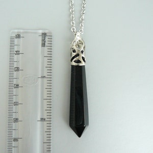 May include: A black onyx pendant necklace with a silver filigree design. The pendant is about 2 inches long and hangs from a silver chain.