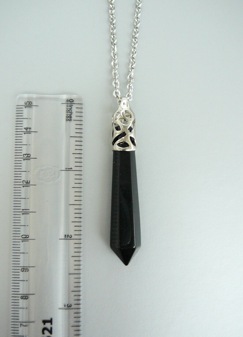 May include: A black onyx pendant necklace with a silver filigree design. The pendant is about 2 inches long and hangs from a silver chain.