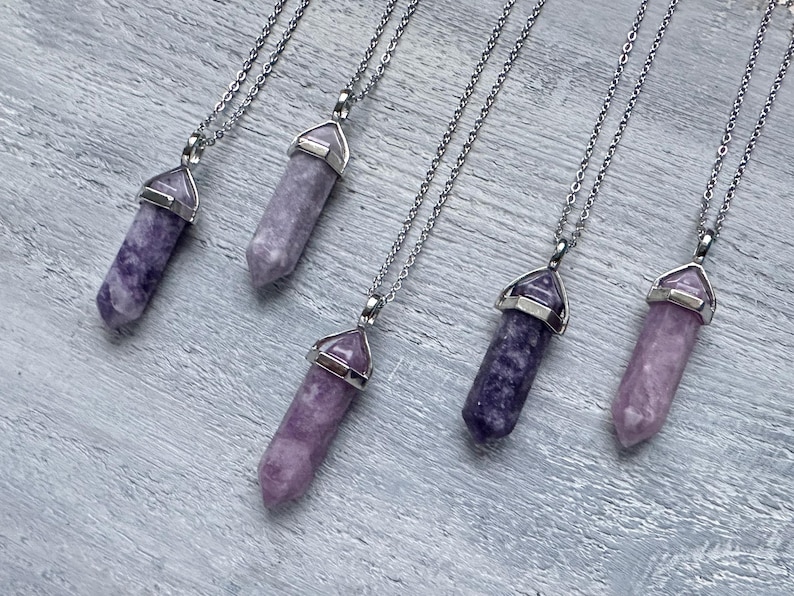 Puede incluir: Cinco collares con colgantes de cristal morado de corte hexagonal puntiagudo suspendidos de cadenas de metal plateado. Cada colgante est&aacute; asegurado con una tapa de metal plateado en la parte superior, mostrando tonos de lavanda y violeta.