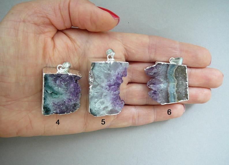Pode incluir: Tr&ecirc;s pingentes de cristal de ametista bruta com bordas e argolas de metal prateado. Cada pingente apresenta uma forma irregular &uacute;nica com estruturas cristalinas roxas e brancas. Os pingentes est&atilde;o marcados com os n&uacute;meros 4, 5 e 6.