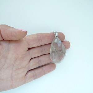 Op de afbeelding: Een heldere kwartskristal hanger aan een zilveren ketting. De hanger is gefacetteerd en heeft een traanvorm.