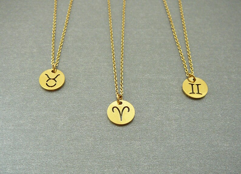 May include: Three gold necklaces with zodiac symbols. The necklaces feature pendants with the symbols for Taurus, Aries, and Gemini.