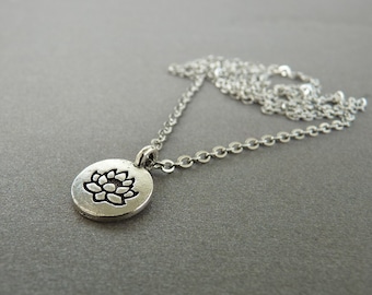 May include: A silver chain necklace with a round pendant featuring a lotus flower design.
