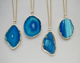 May include: Four gold necklaces with blue agate pendant stones. Each pendant is a different shape and has a unique pattern of blue and white.