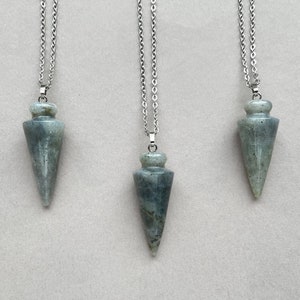 May include: Three silver chain necklaces with grey gemstone pendants in the shape of a point. The pendants are all the same shape and size.