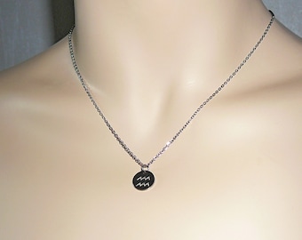 May include: A silver chain necklace with a round pendant featuring the Aquarius zodiac symbol.