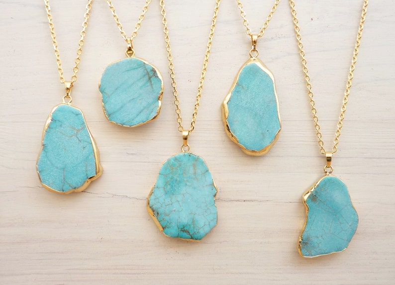 May include: Five gold necklaces with turquoise stone pendants. Each pendant is a different irregular shape and has a gold trim.