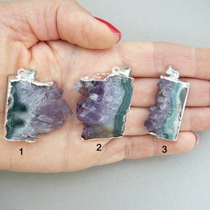 Pode incluir: Tr&ecirc;s pingentes de cristal de ametista bruta com argolas de metal prateado. Cada pingente apresenta pontas de cristal roxo irregulares e uma borda mineral verde-escura. Os pingentes est&atilde;o numerados 1, 2 e 3, exibindo varia&ccedil;&otilde;es naturais.