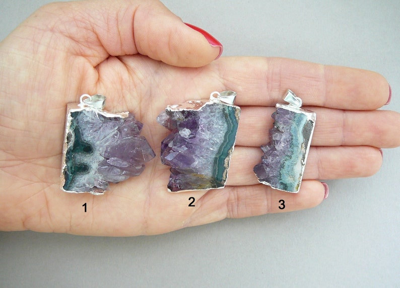 Pode incluir: Tr&ecirc;s pingentes de cristal de ametista bruta com argolas de metal prateado. Cada pingente apresenta pontas de cristal roxo irregulares e uma borda mineral verde-escura. Os pingentes est&atilde;o numerados 1, 2 e 3, exibindo varia&ccedil;&otilde;es naturais.