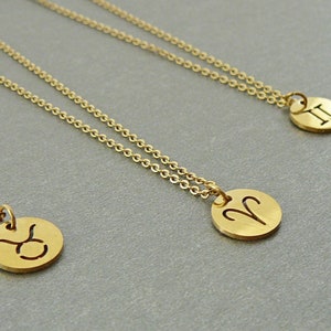 May include: Three gold necklaces with zodiac signs. The necklaces feature a Taurus, Aries, and Gemini pendant.