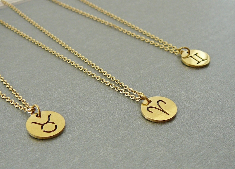 May include: Three gold necklaces with zodiac signs. The necklaces feature a Taurus, Aries, and Gemini pendant.