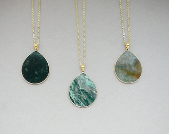 May include: Three gold necklaces with teardrop-shaped pendants made of green agate. Each pendant has a unique pattern of green and brown.