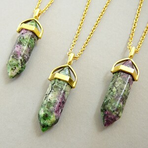 May include: Three gold necklaces with green and pink gemstone pendants. Each pendant is a pointed crystal shape with a gold setting.