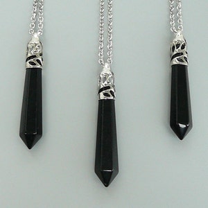 May include: Three black gemstone pendants on silver chains. Each pendant is a pointed, faceted, black gemstone with a silver filigree bail.