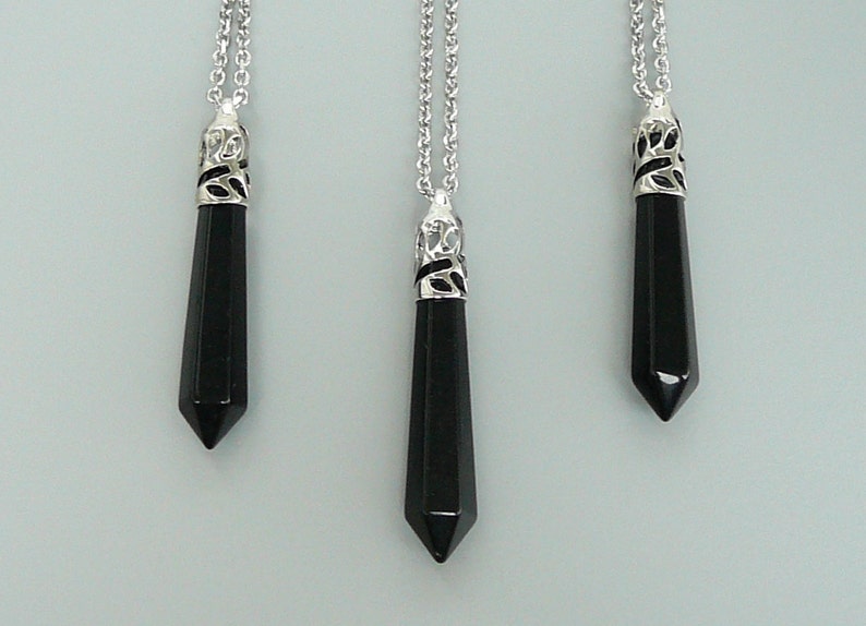 May include: Three black gemstone pendants on silver chains. Each pendant is a pointed, faceted, black gemstone with a silver filigree bail.