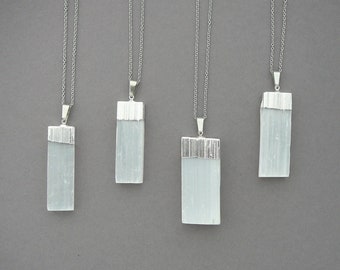 May include: Four silver necklaces with rectangular selenite crystal pendants. The pendants are a light, translucent white with a silver trim.