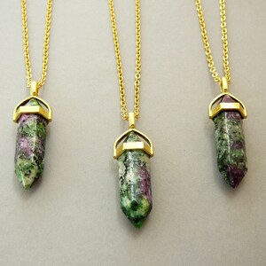 May include: Three gold chain necklaces with green and pink gemstone pendants. Each pendant is a pointed crystal shape with a gold setting.