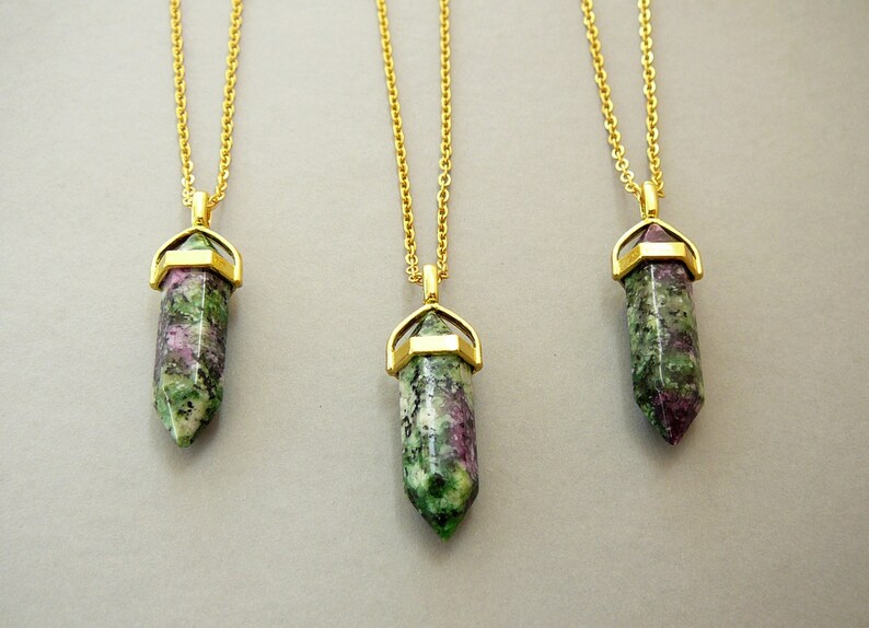 May include: Three gold chain necklaces with green and pink gemstone pendants. Each pendant is a pointed crystal shape with a gold setting.